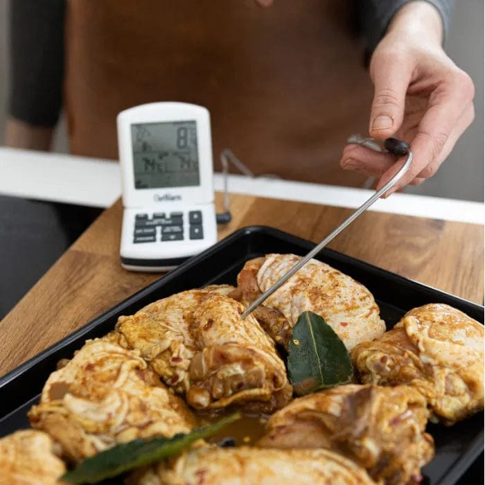 Une personne utilise le Thermomètre et minuterie ChefAlarm de Thermometre.fr pour vérifier la température d'un poulet.