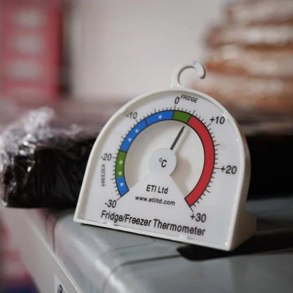 Un Thermomètre pour réfrigérateur ou congélateur avec cadran de 70 mm de Thermometre.fr est posé sur une table.