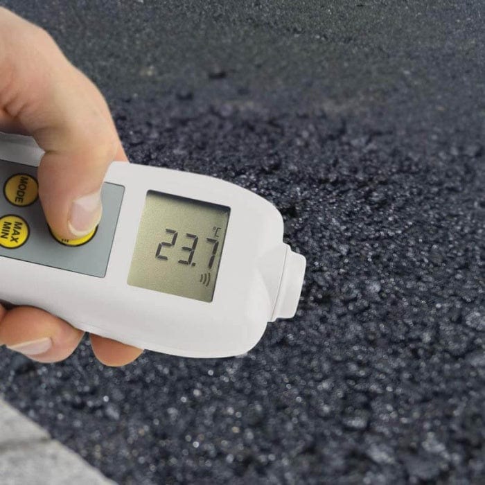 Une personne au Royaume-Uni tenant un thermomètre infrarouge Thermomètre.fr à émissivité réglable sur une route.