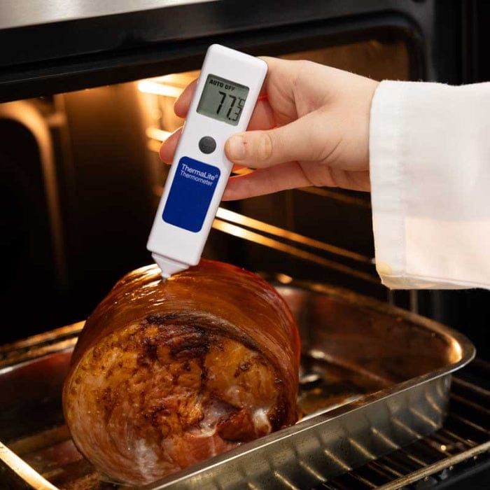 Un chef utilise un NOUVEAU Thermomètre à sonde alimentaire ThermaLite de Thermomètre.fr pour vérifier la température d'un jambon rôti dans un four.