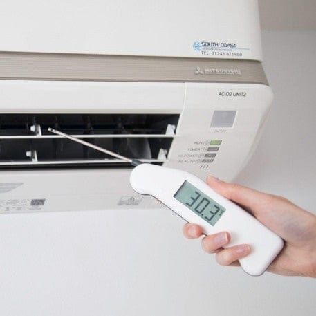 une personne tenant un Thermapen® Air - Idéal pour CVC de Thermometre.fr devant un climatiseur.