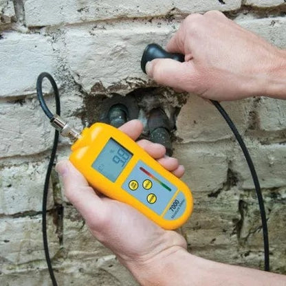 une personne utilisant un Testeur d'humidité 7000 avec sonde de Thermometre.fr sur un mur de briques.