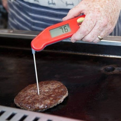 une personne utilisant un thermometre.fr thermapen Burger pour vérifier la température d'un burger.