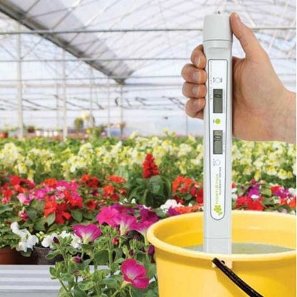 Une personne tenant un testeur de nutriments HortiStick de Thermometre.fr dans une serre.